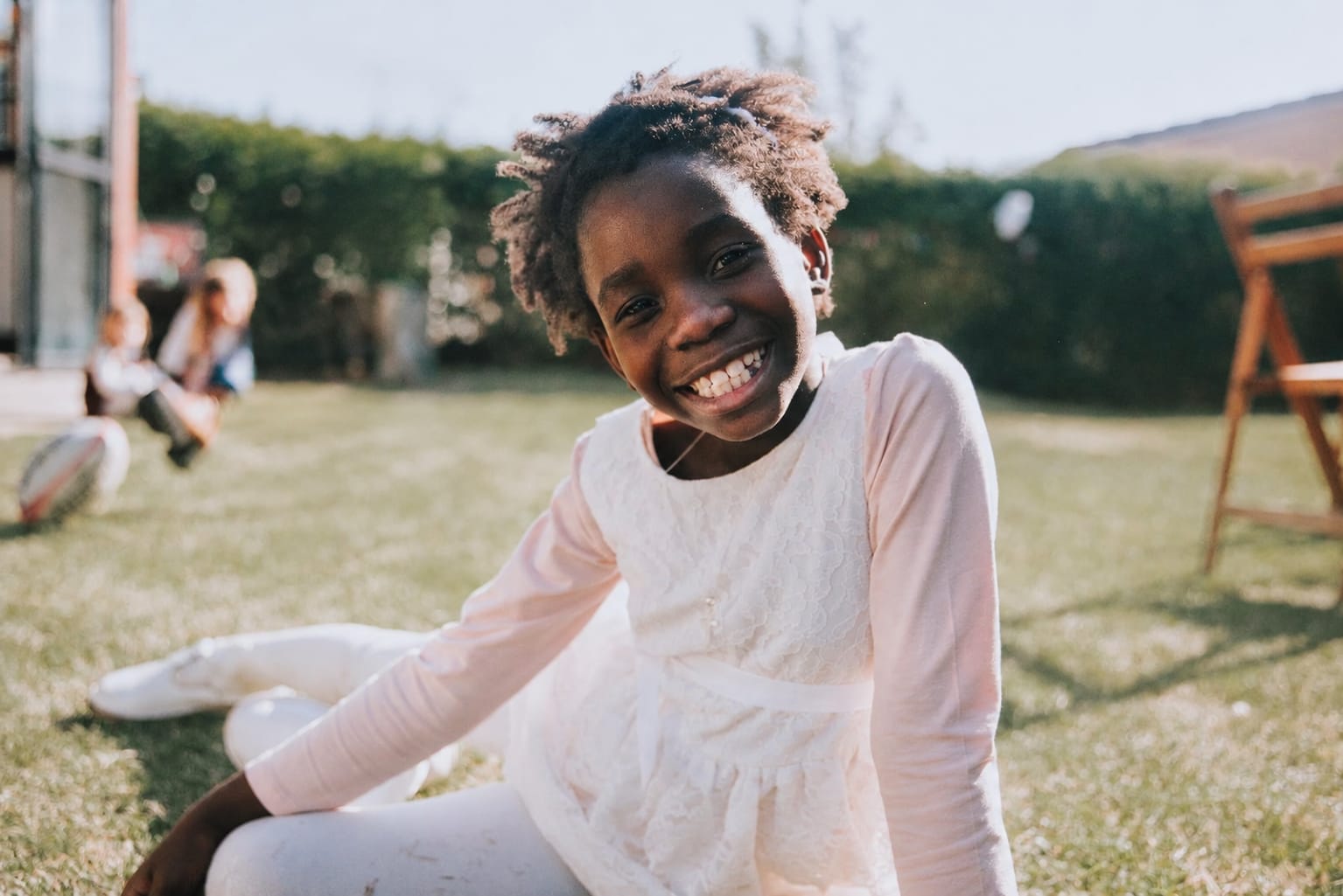 Kim en su infancia, sonriendo en un jardín con un vestido blanco